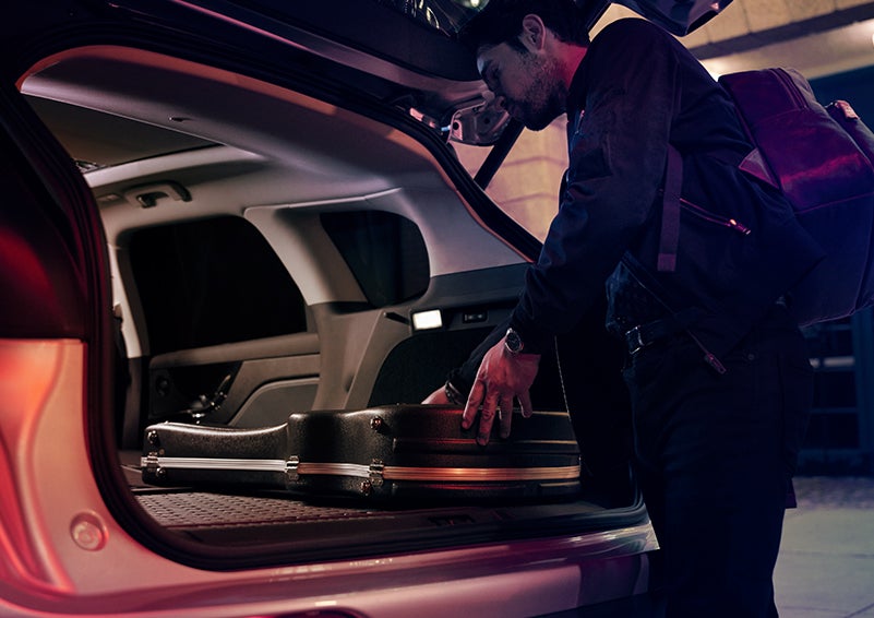 A man is shown loading cargo into the rear of a 2024 Lincoln Corsair® SUV with the second-row seats folded flat. | Sentry Lincoln in Medford MA