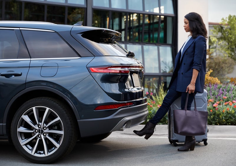 A woman with luggage and a bag opens the available hands-free liftgate by kicking her foot under the bumper | Sentry Lincoln in Medford MA