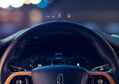 The available head-up display projects data on the windshield above the steering wheel inside a 2022 Lincoln Corsair as the driver navigates the city at night | Sentry Lincoln in Medford MA
