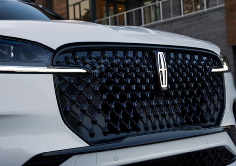 The black grille of a white 2025 Lincoln Aviator® SUV is shown with its fog lights on. | Sentry Lincoln in Medford MA