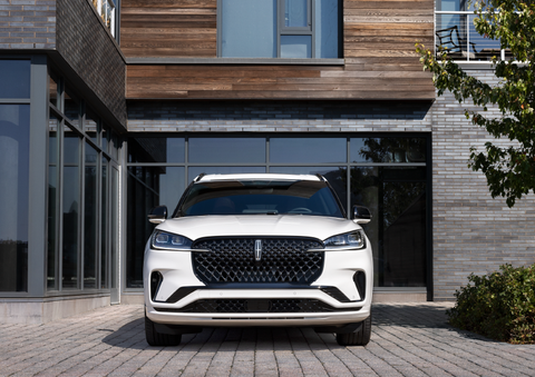 A white 2025 Lincoln Aviator® SUV is shown parked outside a modern building with gray brick and wood accents. | Sentry Lincoln in Medford MA