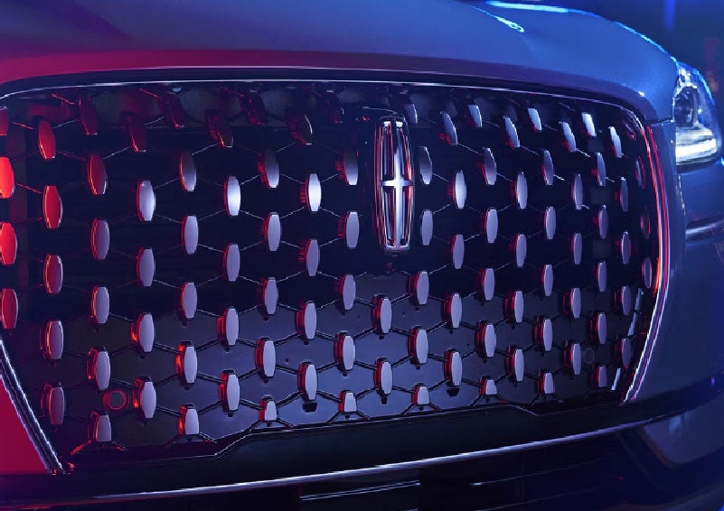 The grille of a 2025 Lincoln Corsair® SUV reflects neon light at night. | Sentry Lincoln in Medford MA