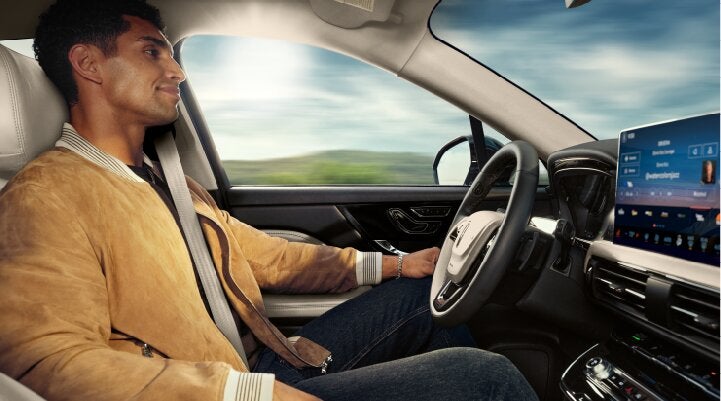 A person is shown using Lincoln BlueCruise hands-free highway driving technology on a divided highway called a Hands-Free Blue Zone. | Sentry Lincoln in Medford MA