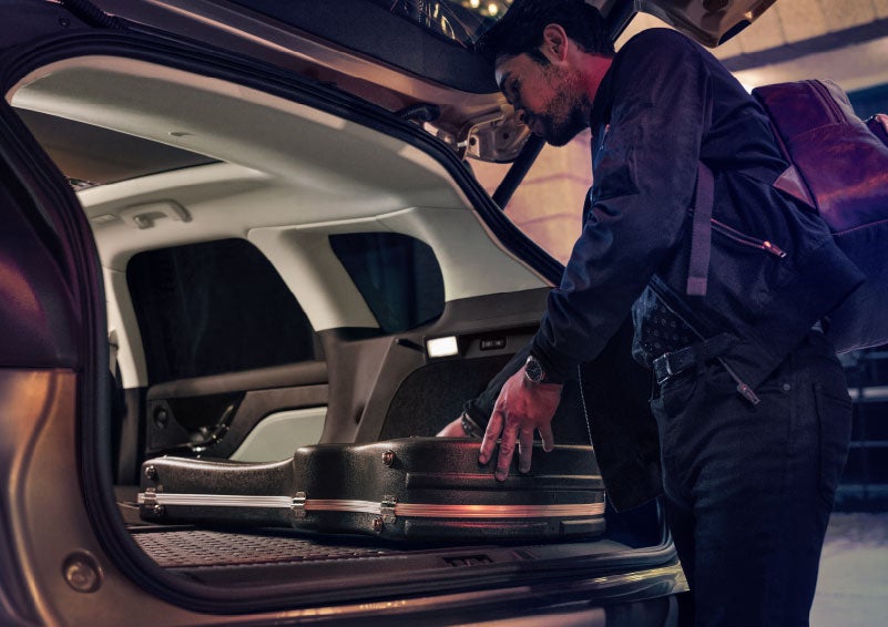A man is shown loading cargo into the rear of a 2024 Lincoln Corsair® SUV with the second-row seats folded flat. | Sentry Lincoln in Medford MA