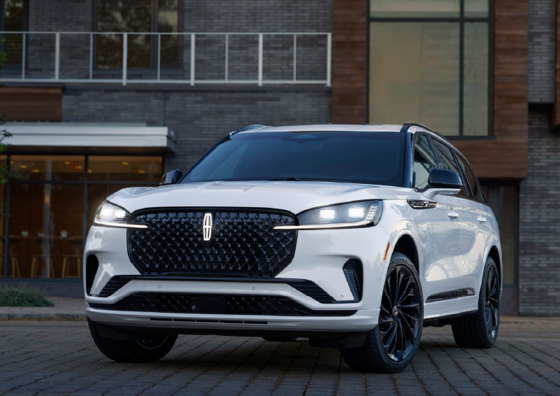A 2026 Lincoln Aviator® Reserve model is shown with the available Jet Appearance Package parked near a restaurant. | Sentry Lincoln in Medford MA