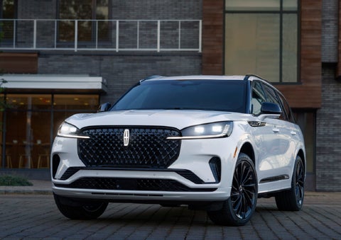 A 2026 Lincoln Aviator® Reserve model is shown with the available Jet Appearance Package parked near a restaurant. | Sentry Lincoln in Medford MA