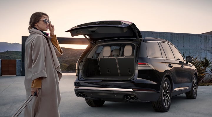 A woman approaches a 2026 Lincoln Aviator® SUV with its rear liftgate open. | Sentry Lincoln in Medford MA