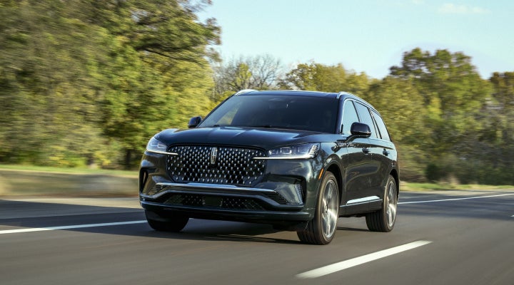 A 2026 Lincoln Black Label™ Aviator® SUV is being driven down a road lined with trees. | Sentry Lincoln in Medford MA