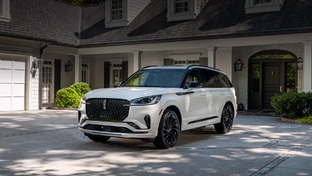 A white 2026 Lincoln Aviator® SUV is parked in the driveway of a luxury home. | Sentry Lincoln in Medford MA