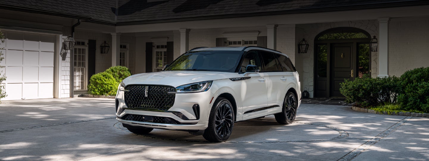 A white 2026 Lincoln Aviator® SUV is parked in the driveway of a luxury home. | Sentry Lincoln in Medford MA