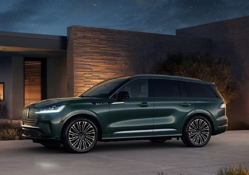 A green 2027 Lincoln Aviator® SUV is parked outside a contemporary home. | Sentry Lincoln in Medford MA