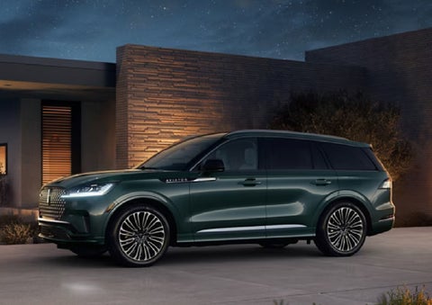 A green 2027 Lincoln Aviator® SUV is parked outside a contemporary home. | Sentry Lincoln in Medford MA