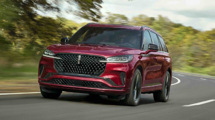 A 2027 Lincoln Aviator® SUV is being driven on a country road | Sentry Lincoln in Medford MA