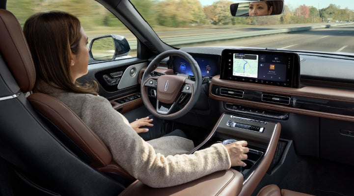 A 2027 Lincoln Aviator® SUV is being driven hands-free on a highway lined with trees. | Sentry Lincoln in Medford MA