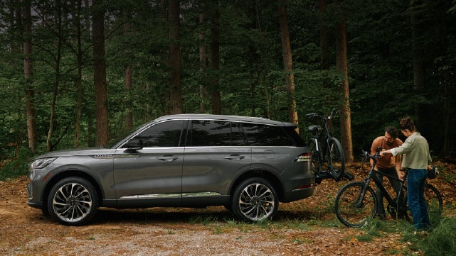 A father and son load e-bikes on a bike rack attached to a 2027 Lincoln Aviator® SUV. | Sentry Lincoln in Medford MA
