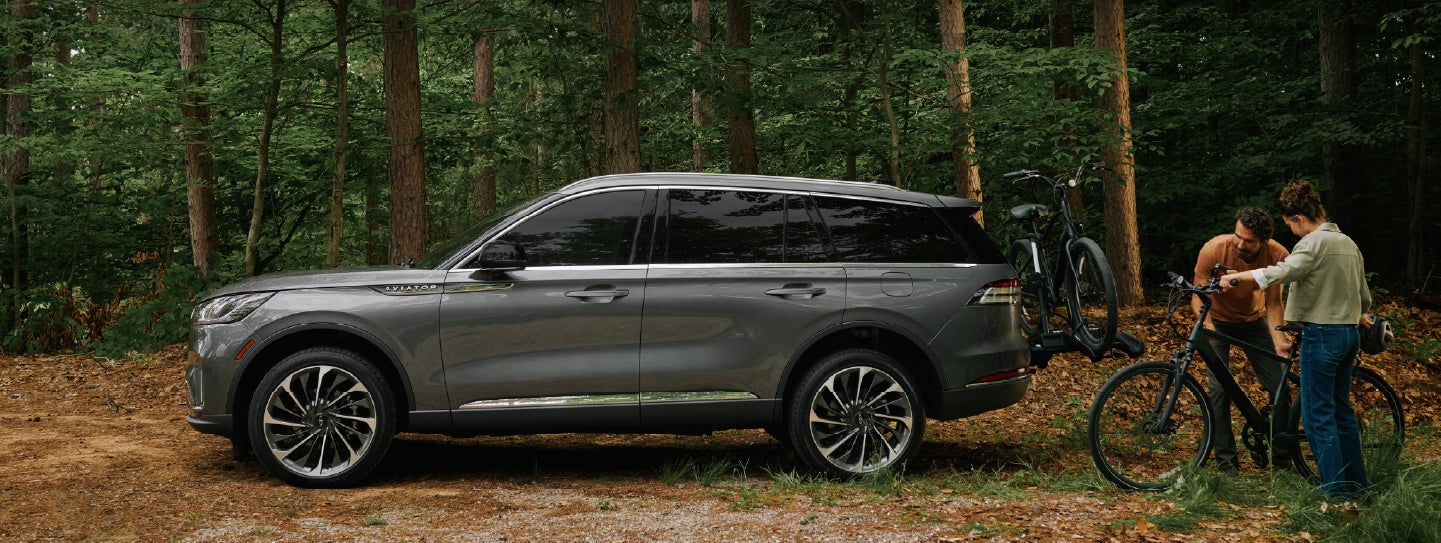 A father and son load e-bikes on a bike rack attached to a 2027 Lincoln Aviator® SUV. | Sentry Lincoln in Medford MA